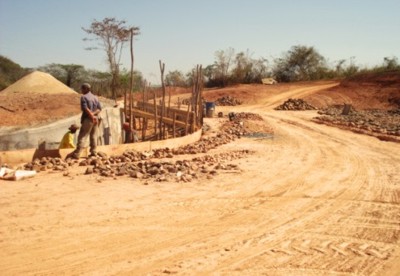 e) Detalhe da concretagem do canal extravasor lateral, contornando o macio de terra da barragem.